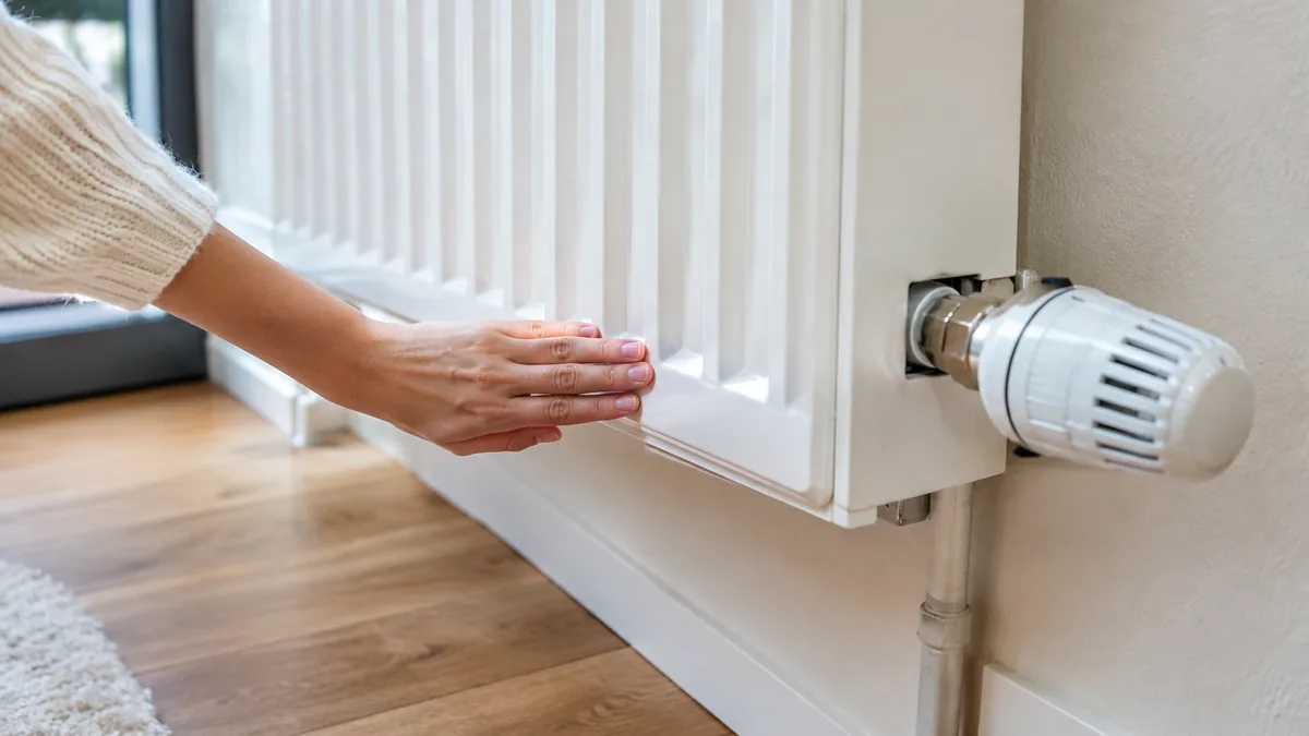 Main posée sur le bas d'un radiateur pour en vérifier la température